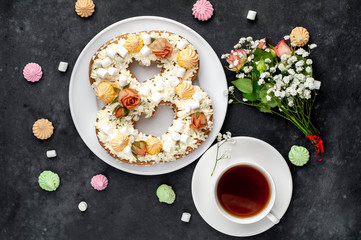tea and cake in the form of 8 is decorated with flowers, cream cheese, marshmallows, Bizet on a stone background. romantic delicious breakfast on International Women's Day March 8