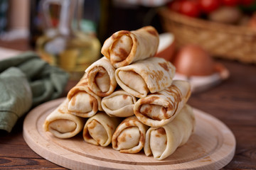 Russian pancakes with filling, lying on a wooden board with a slide