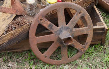 Close up of an old rusty wagon wheel with other junk at a flea market