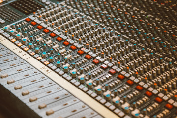 Professional audio mixing console with faders and adjusting knobs