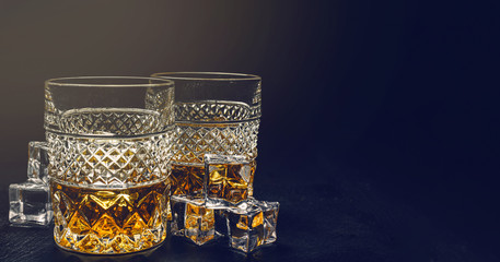 Obraz na płótnie Canvas two expensive glasses of whiskey with ice on a black stone tray