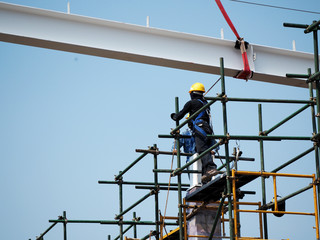 Construction workers working on scaffolding with blue sky at construction site