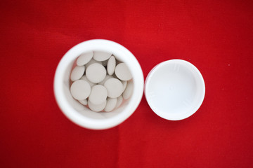  pills in a jar on a red background