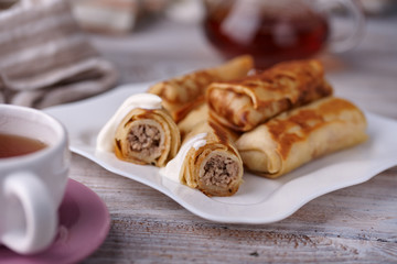 Russian pancakes with filling, lying on a plate with a slide
