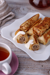 Russian pancakes with filling, lying on a plate with a slide