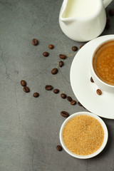 cup of black coffee, milk jug with milk and coffee beans on a black background and place for text