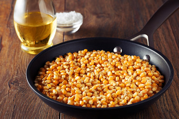 Corn maize or kernel seed in a frying pan on a wooden kitchen table