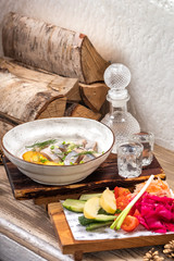 Restaurant Seafood Menu with Salted herring with onions rings and boiled diced potato on elegant restaurant plate with set of alcoholic cold vodka and assorted pickled. Russian food background.