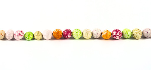 Fototapeta na wymiar colored sweet candy peanuts in icing, similar to bird eggs, lie in a row on a white background