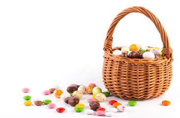 colorful candies and candies similar to eggs in an Easter basket on a pink background with a copy of the space