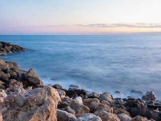 Fototapeta na wymiar Evening time long exposure photo of waves crashing on rocks in Paphos, Cyprus,