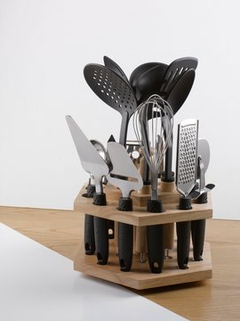 Kichen utensil set and holder on wooden surface. White backgound