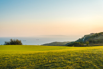 Obraz premium Beautiful landscape - green grass meadow and the sea in the background. Golf club meadow and the sea