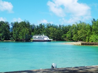 Blue waters of a lagoon with a yacht moored in the waters in Peleliu, Palau.