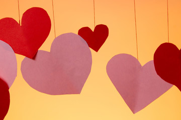 hearts red and pink on a string valentines day love on an orange background. close up copy space