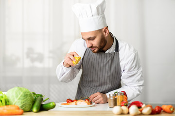 Chef Cooking Fish Squeezing Lemon On Salmon Steak In Kitchen