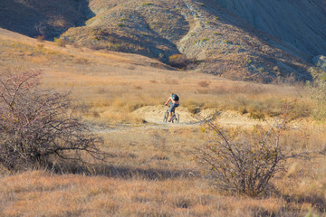 Obraz premium Cyclist rides on a dirt road in the highlands