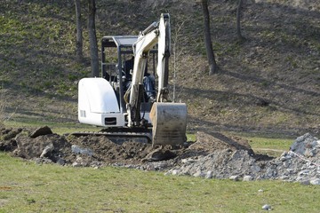A mini excavator digs a ditch for laying pipes.