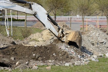 A mini excavator digs a ditch for laying pipes.