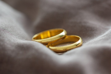 Two wedding gold rings on brown background