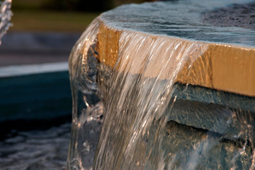 Naklejka na ściany i meble Falling water stream at a fountain edge