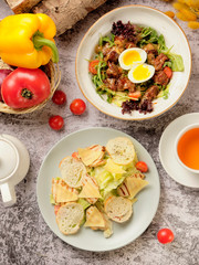 Restaurant cold caesar salad with chicken, cherry tomato, green leaves and herbs and leaf salad with poached egg and red meat. Dinner Idea. Food and drink concept.