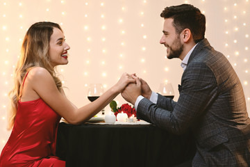 Young Man And Woman Holding Hands On Romantic Date In Restaurant