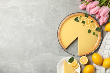 Composition with lemon tart and tulips on grey background, top view