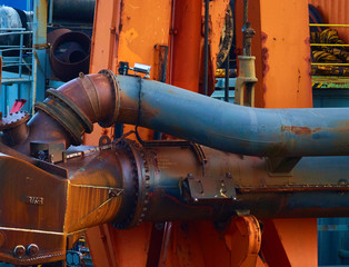 Pipes and pipe systems on a tanker, painted blue and orange, with large rust spots