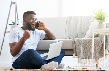 Happy african guy hearing good news by phone
