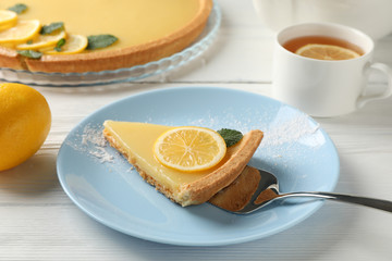 Fototapeta na wymiar Composition with lemon tart slice on plate on white wood background, close up