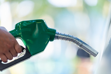 Man Handle pumping gasoline fuel nozzle to refuel. Vehicle fueling facility at petrol station....