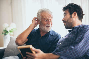 adult hipster son and old senior father stay for work at home, two generations have a beard talking together and relaxing with smile, happy enjoy living to isolation quarantine at home in Father's Day