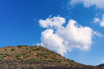 White cloud in a blue sky just above a hill. Lanzarote Island, Canary, Spain. 