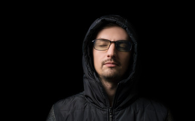 Naklejka na ściany i meble young man in a hood and glasses on a black background