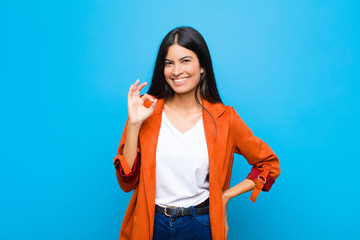 young pretty latin woman feeling happy, relaxed and satisfied, showing approval with okay gesture,...