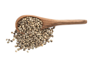 Overturned brown wooden spoon with spilled hemp seeds seen from the side and isolated on white background