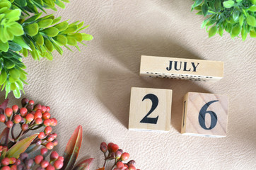 July 26, Number cube design with flower on white lether background.