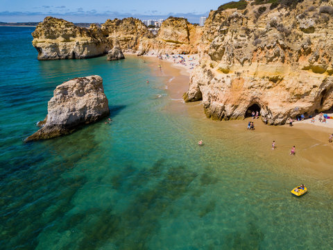 Aerial shot from above of blue water of white rocky cliffs and sand of the shoreline of Algarve, Portugal.