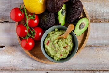 Tasty and healthy mexican snack: avocado guacamole. Homemade, served on a wooden rustic table with raw ingredients. Delicious and low calorie meal. Copy space for text, flat lay