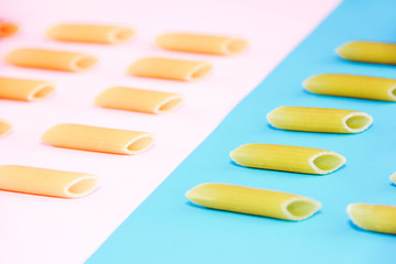 natural long tubular pasta on a pink and blue background