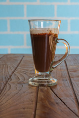 Iced chocolate in tall glass on wooden table served in morning.