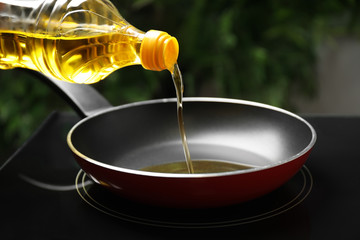 Pouring cooking oil from bottle into frying pan, closeup