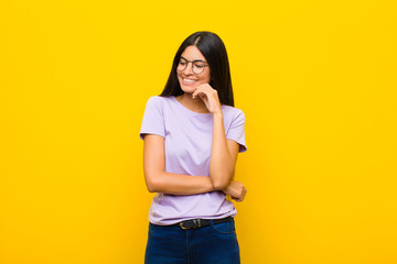 young pretty latin woman smiling with a happy, confident expression with hand on chin, wondering...