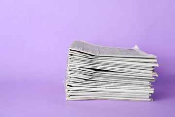 Stack of newspapers on light violet background. Journalist's work