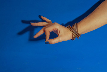 female hand with blue nails showing ok sign on blue background