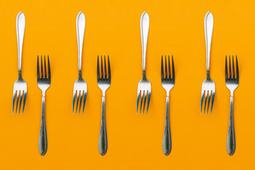 Forks on an orange background. Stainless steel cutlery for food.