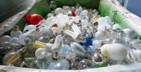 selective focus view of large recycling bin filled with many different size and color light bulbs