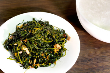 Stir fried salted Hemp leaf and Boiled rice on dark wooden background
