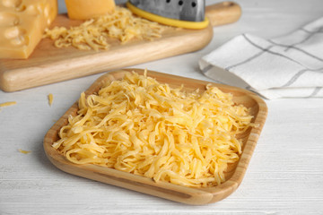 Delicious grated cheese on white wooden table